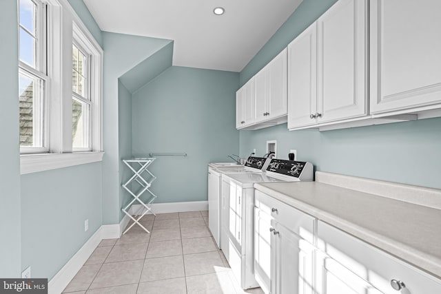 washroom featuring washing machine and dryer, light tile patterned floors, and cabinets