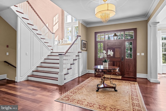 foyer with ornamental molding, decorative columns, an inviting chandelier, and dark hardwood / wood-style floors