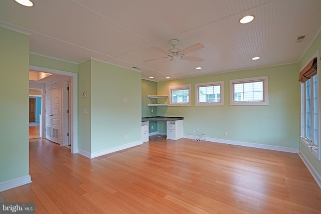 unfurnished living room featuring built in desk, light hardwood / wood-style floors, ceiling fan, and crown molding