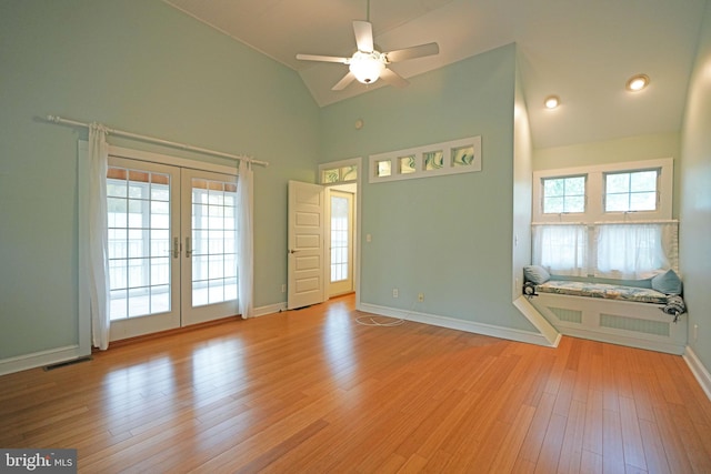 empty room with ceiling fan, light hardwood / wood-style flooring, french doors, and high vaulted ceiling