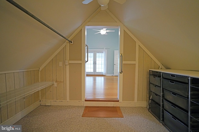 bonus room featuring wood walls, wood-type flooring, lofted ceiling, ceiling fan, and french doors