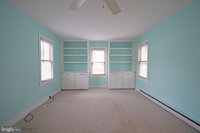 carpeted empty room with ceiling fan, baseboard heating, and a wealth of natural light