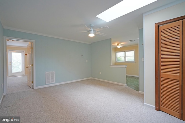 unfurnished room with light colored carpet, a healthy amount of sunlight, crown molding, and a skylight