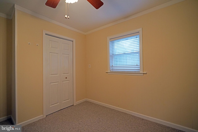 unfurnished bedroom with a closet, carpet, ceiling fan, and crown molding