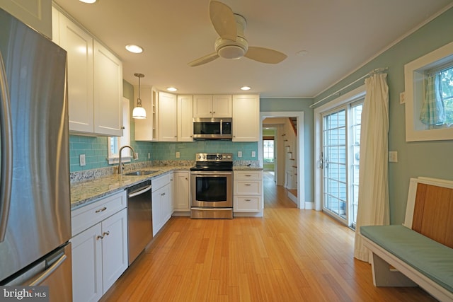 kitchen with stainless steel appliances, white cabinets, light hardwood / wood-style floors, and sink