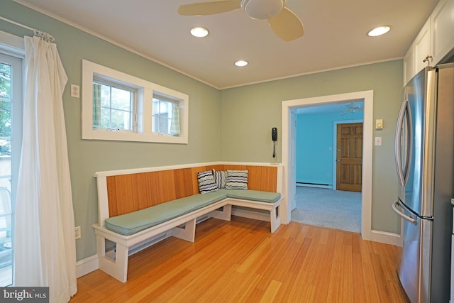 interior space featuring light hardwood / wood-style floors, ornamental molding, ceiling fan, and a baseboard heating unit