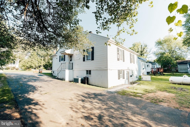 view of property exterior with a lawn and central air condition unit