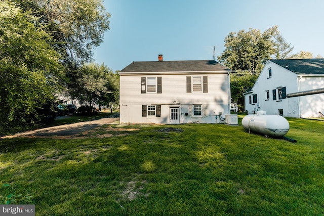 back of property featuring a yard and central AC