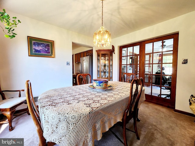 carpeted dining space with french doors and a chandelier