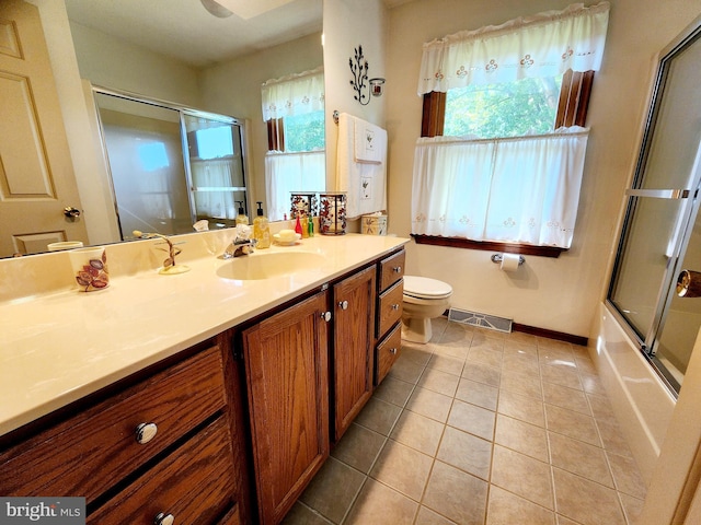 full bathroom with tile patterned floors, vanity, bath / shower combo with glass door, and toilet