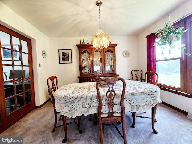 carpeted dining room with a chandelier