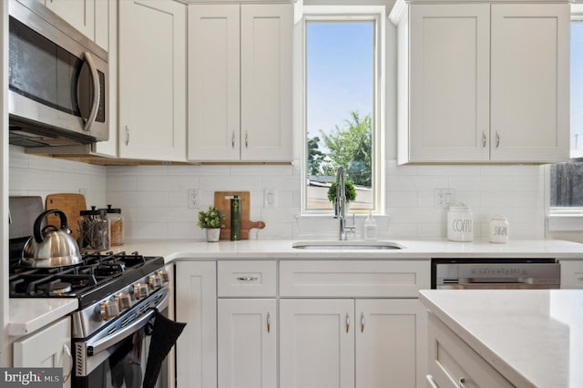 kitchen with white cabinets, appliances with stainless steel finishes, backsplash, and sink