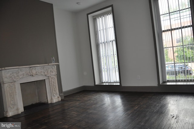 unfurnished living room with dark wood-type flooring and a fireplace