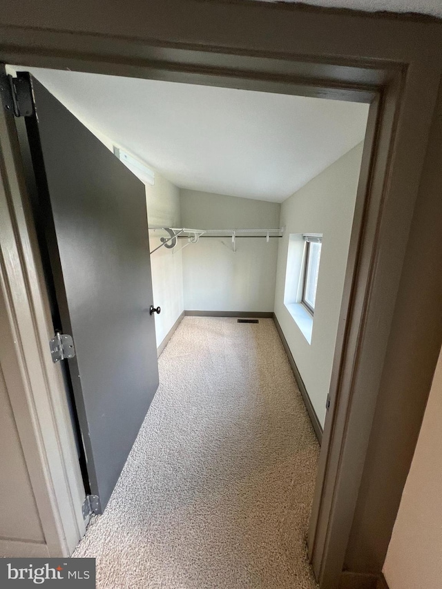 corridor featuring light carpet and vaulted ceiling