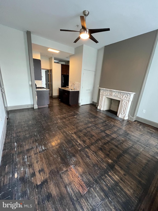 unfurnished living room with a premium fireplace, ceiling fan, and sink