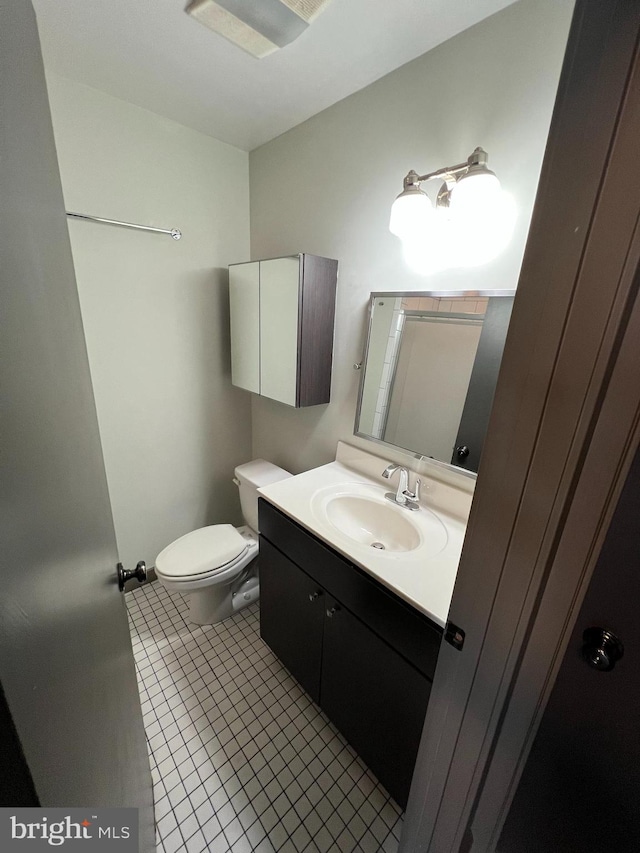 bathroom featuring tile patterned flooring, toilet, and vanity