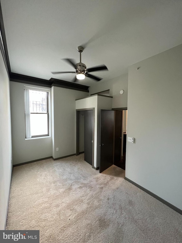 unfurnished bedroom with ceiling fan, ornamental molding, and light carpet