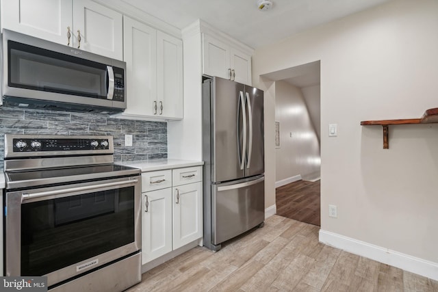 kitchen featuring light wood-type flooring, appliances with stainless steel finishes, white cabinets, and decorative backsplash