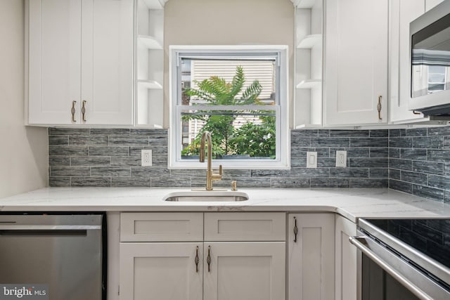 kitchen featuring white cabinets, appliances with stainless steel finishes, light stone counters, sink, and tasteful backsplash