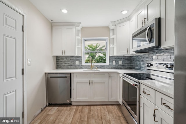 kitchen with white cabinets, light wood-type flooring, stainless steel appliances, sink, and decorative backsplash