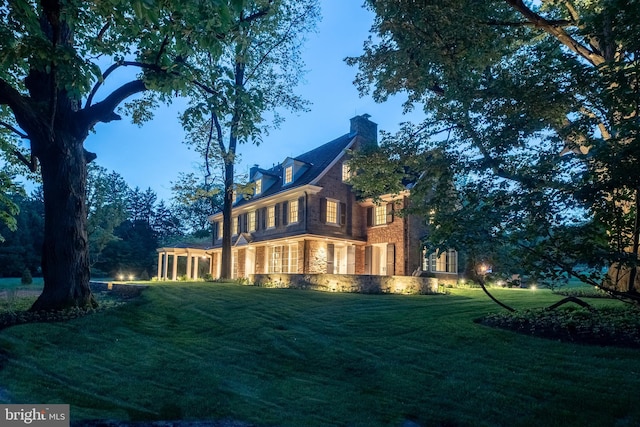 back house at dusk with a lawn