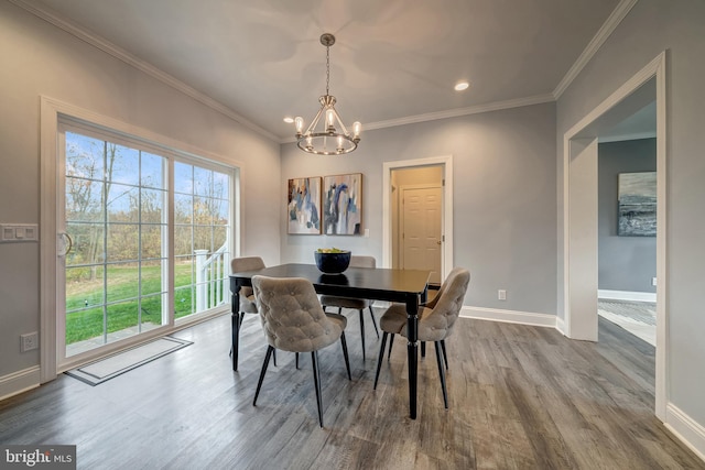 dining area featuring an inviting chandelier, crown molding, baseboards, and wood finished floors