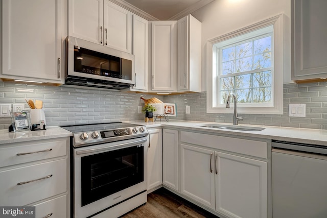 kitchen with stainless steel appliances, dark wood-style flooring, a sink, white cabinetry, and backsplash