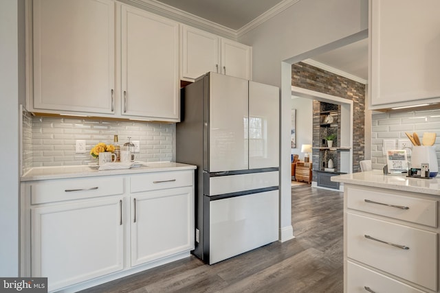 kitchen featuring dark wood-style flooring, freestanding refrigerator, crown molding, white cabinetry, and backsplash