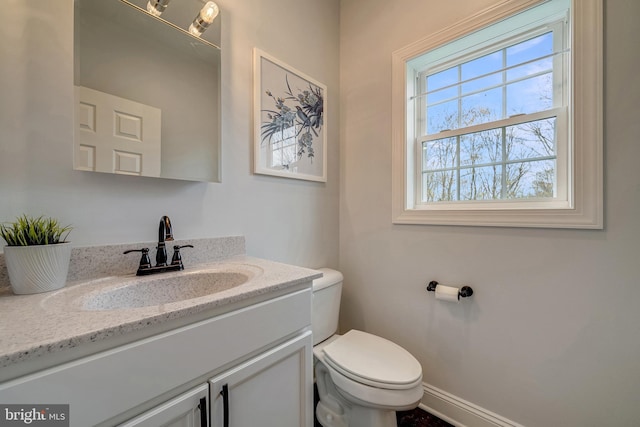 bathroom with toilet, vanity, and baseboards