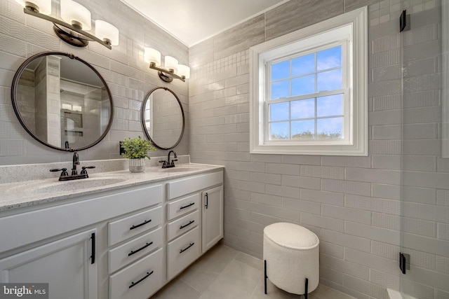 full bathroom with a sink, tile walls, and double vanity