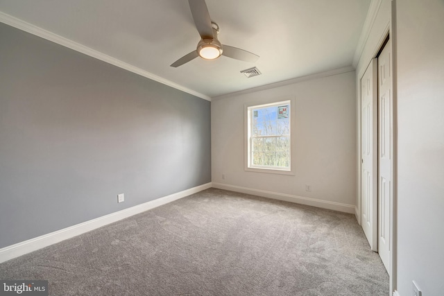 unfurnished bedroom featuring baseboards, visible vents, crown molding, and carpet flooring