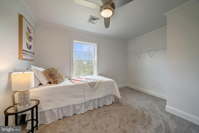 carpeted bedroom featuring baseboards, visible vents, ceiling fan, and crown molding