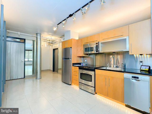 kitchen with light brown cabinets, light tile patterned flooring, sink, track lighting, and appliances with stainless steel finishes