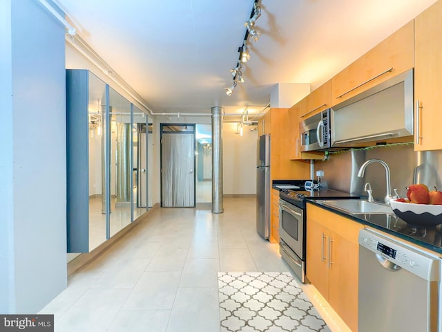 kitchen with light tile patterned floors, appliances with stainless steel finishes, sink, and rail lighting