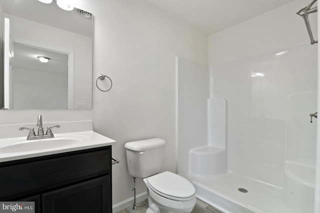 full bath with baseboards, vanity, toilet, and walk in shower