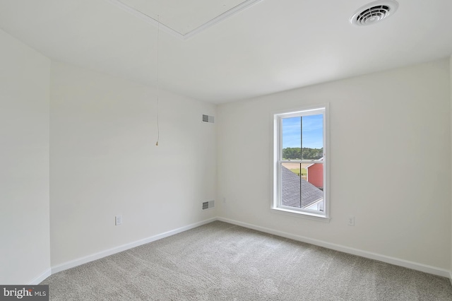 carpeted empty room featuring attic access, visible vents, and baseboards