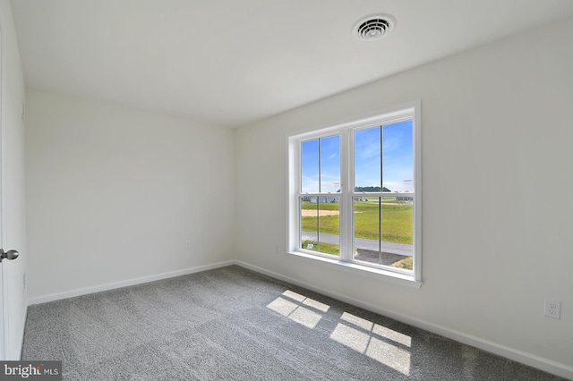 empty room featuring carpet, visible vents, and baseboards