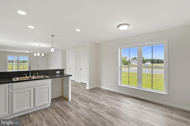 kitchen featuring a chandelier, a sink, baseboards, light wood-style floors, and dark countertops