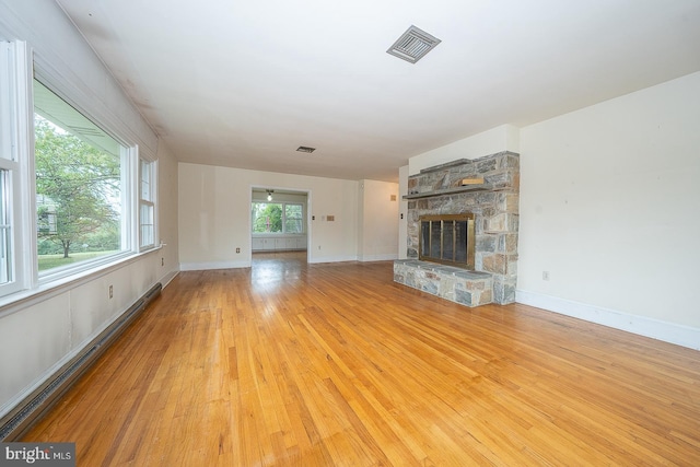 unfurnished living room with a stone fireplace and light hardwood / wood-style floors