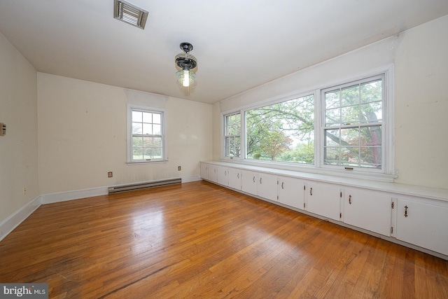 empty room with a baseboard radiator and light hardwood / wood-style floors