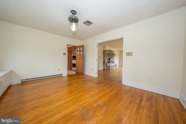 unfurnished room featuring a baseboard radiator and light hardwood / wood-style flooring