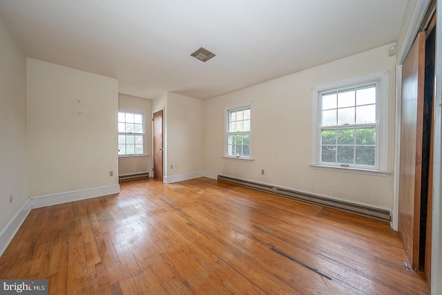 spare room featuring a baseboard radiator, light hardwood / wood-style floors, and plenty of natural light