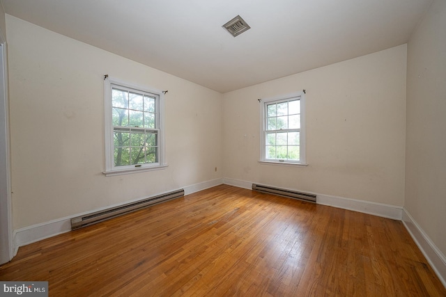 empty room featuring baseboard heating and hardwood / wood-style flooring