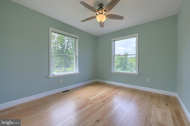 spare room featuring light hardwood / wood-style flooring, ceiling fan, and a healthy amount of sunlight