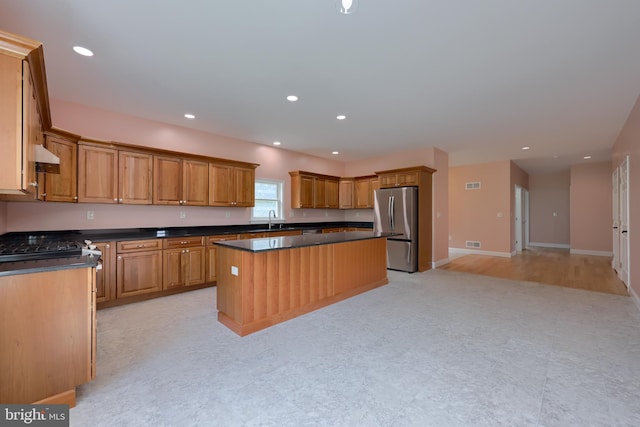 kitchen with stainless steel fridge, a center island, sink, and light hardwood / wood-style floors