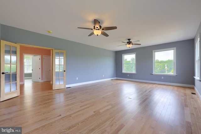 empty room featuring ceiling fan, french doors, and light hardwood / wood-style floors