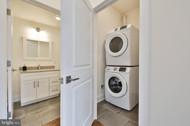 laundry area with light tile patterned flooring, sink, and stacked washer and dryer