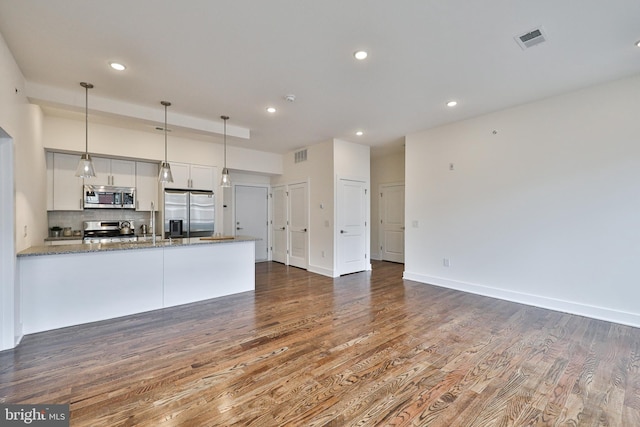 kitchen featuring white cabinets, hardwood / wood-style flooring, stone counters, stainless steel appliances, and kitchen peninsula