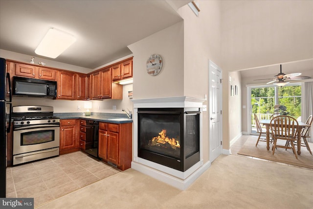 kitchen featuring light carpet, sink, black appliances, ceiling fan, and a multi sided fireplace