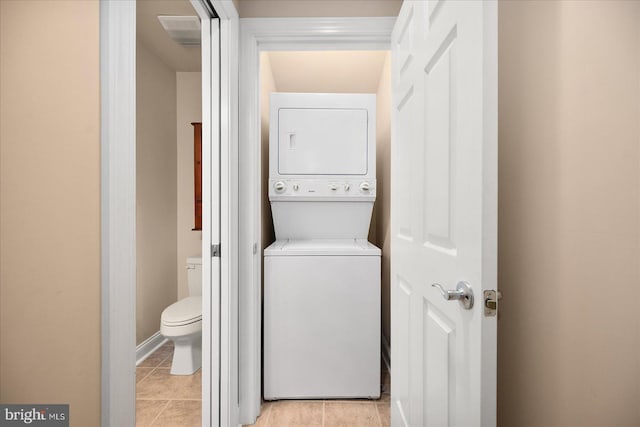 laundry area with light tile patterned floors and stacked washer / drying machine